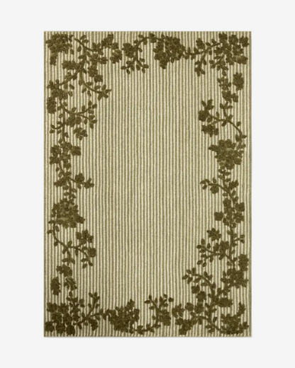 A rectangular area rug with a vertical striped pattern in beige and brown, framed by a dark olive green floral vine border, shown against a solid gray background.
