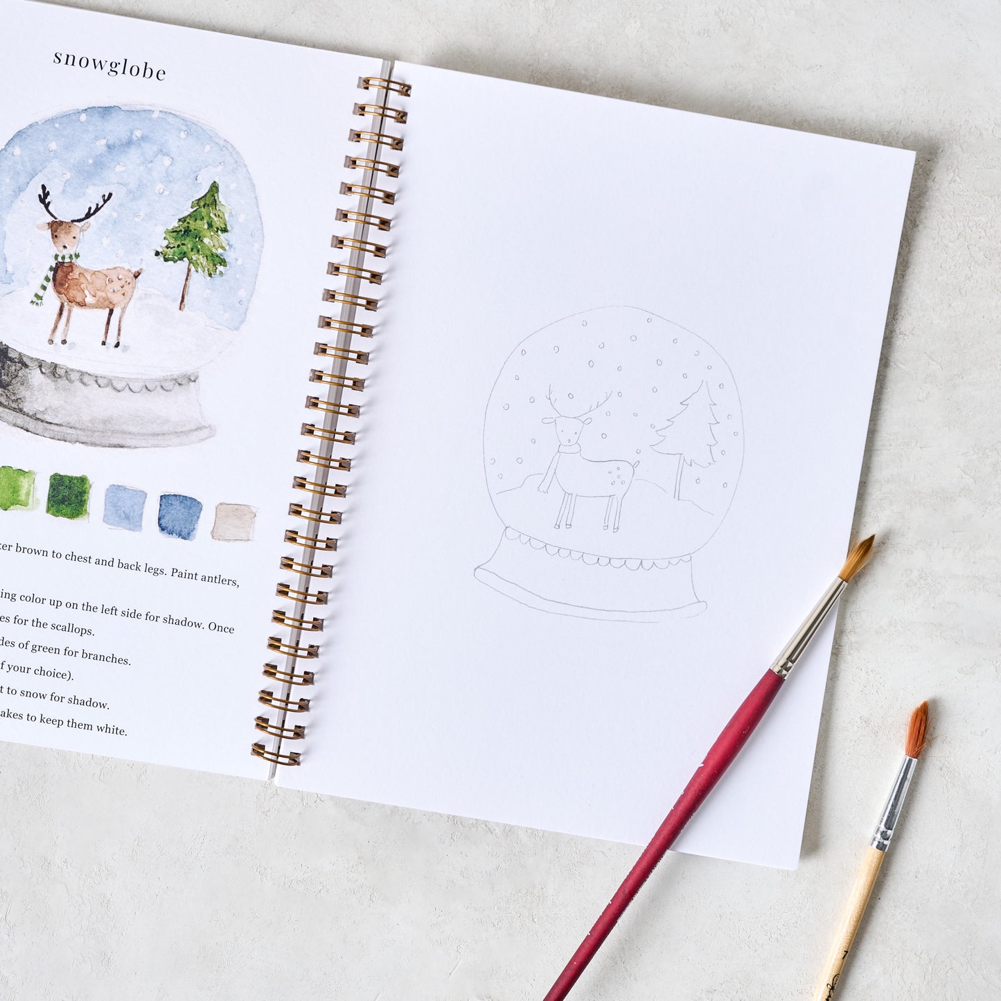 Winter Watercolor Workbook open with paintbrushes