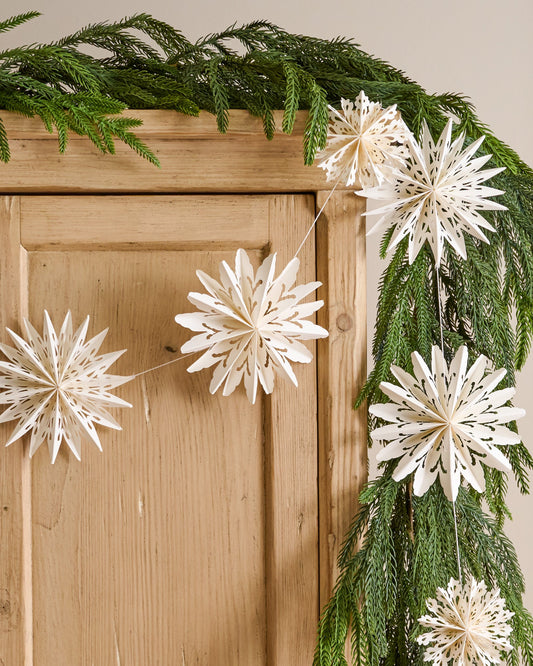 Whimsical Snowflake Garland shown hung on cabinet