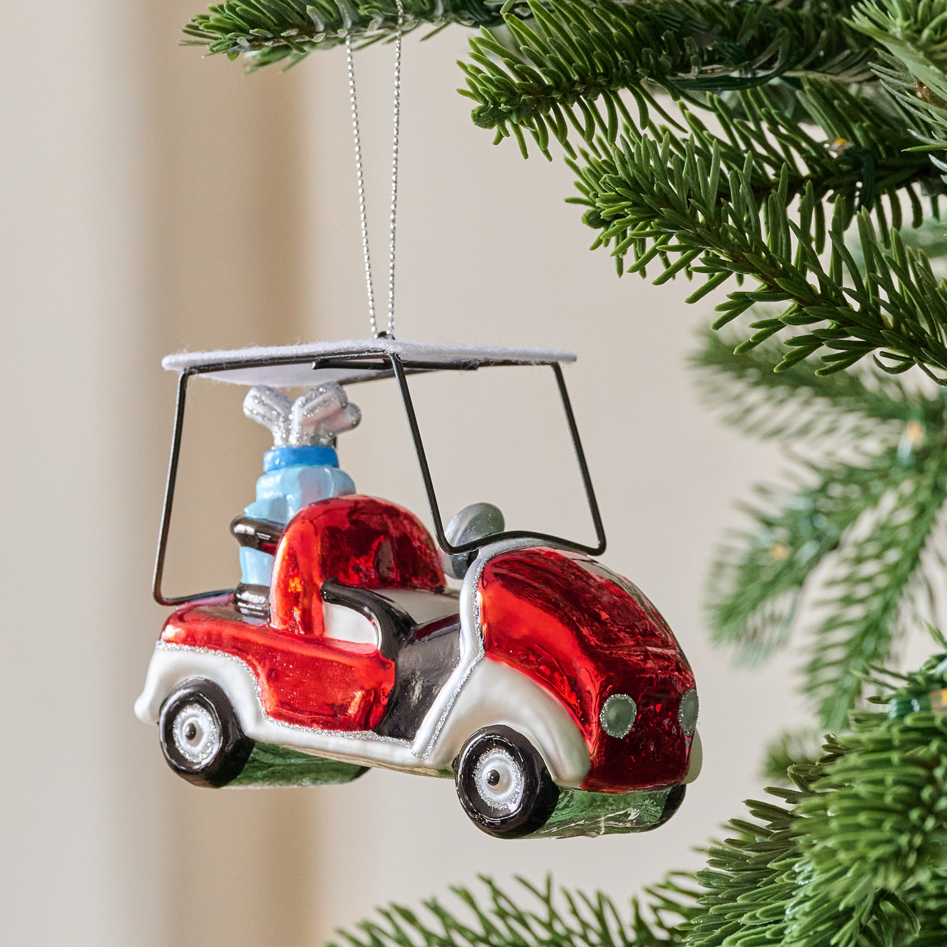 Glass Golf Cart Ornament shown hung from tree
