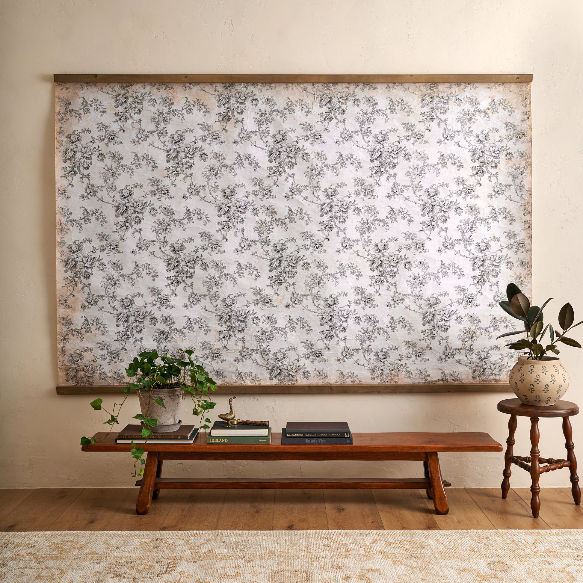 Oversized Heirloom Garden Tapestry in a room with wooden bench coffee table books and greenery plants