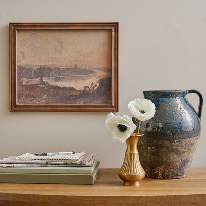 Spring Reflection Framed Print on a wall above console table with stacked books and decorative accessories and vases
