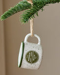 Green Magnolia Campfire Mug Ornament shown hung from tree