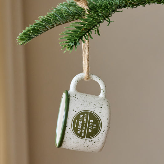 Green Magnolia Campfire Mug Ornament shown hung from tree