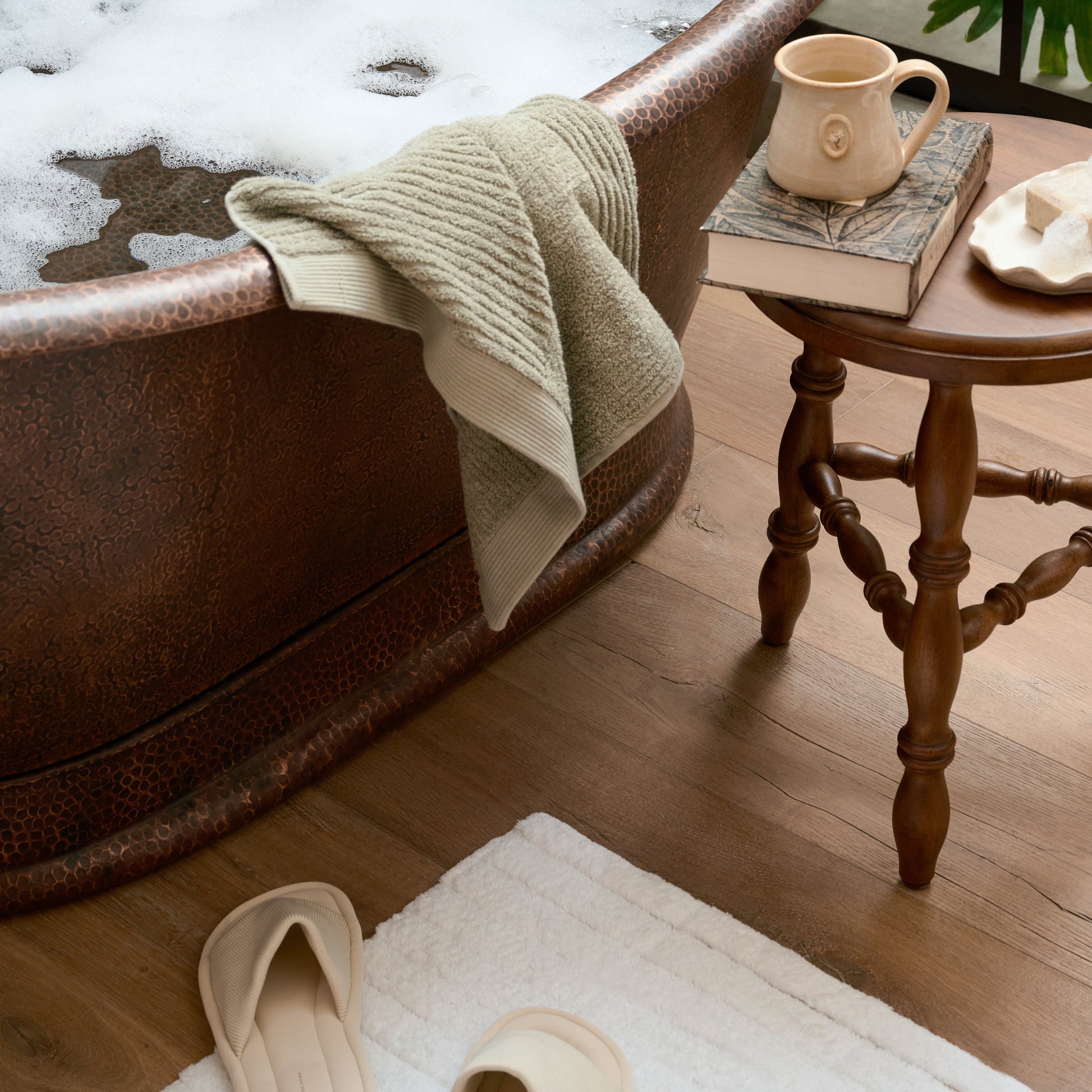 Lavinia Turned Leg Stool (short) next to a bathtub