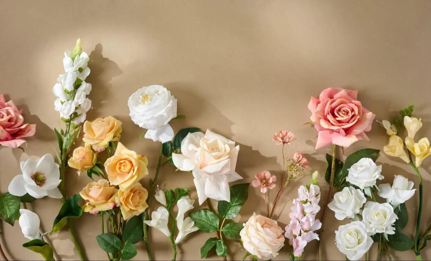 An assortment of faux florals on a brown background. 