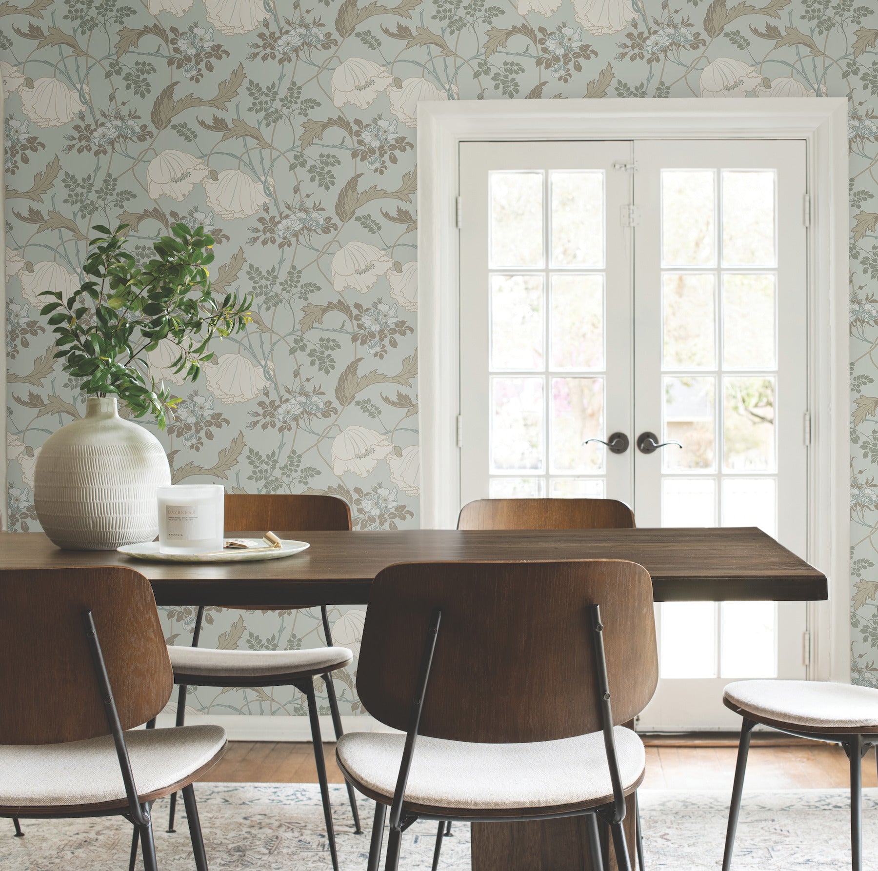 Floral wallpaper behind wood dining table and chairs