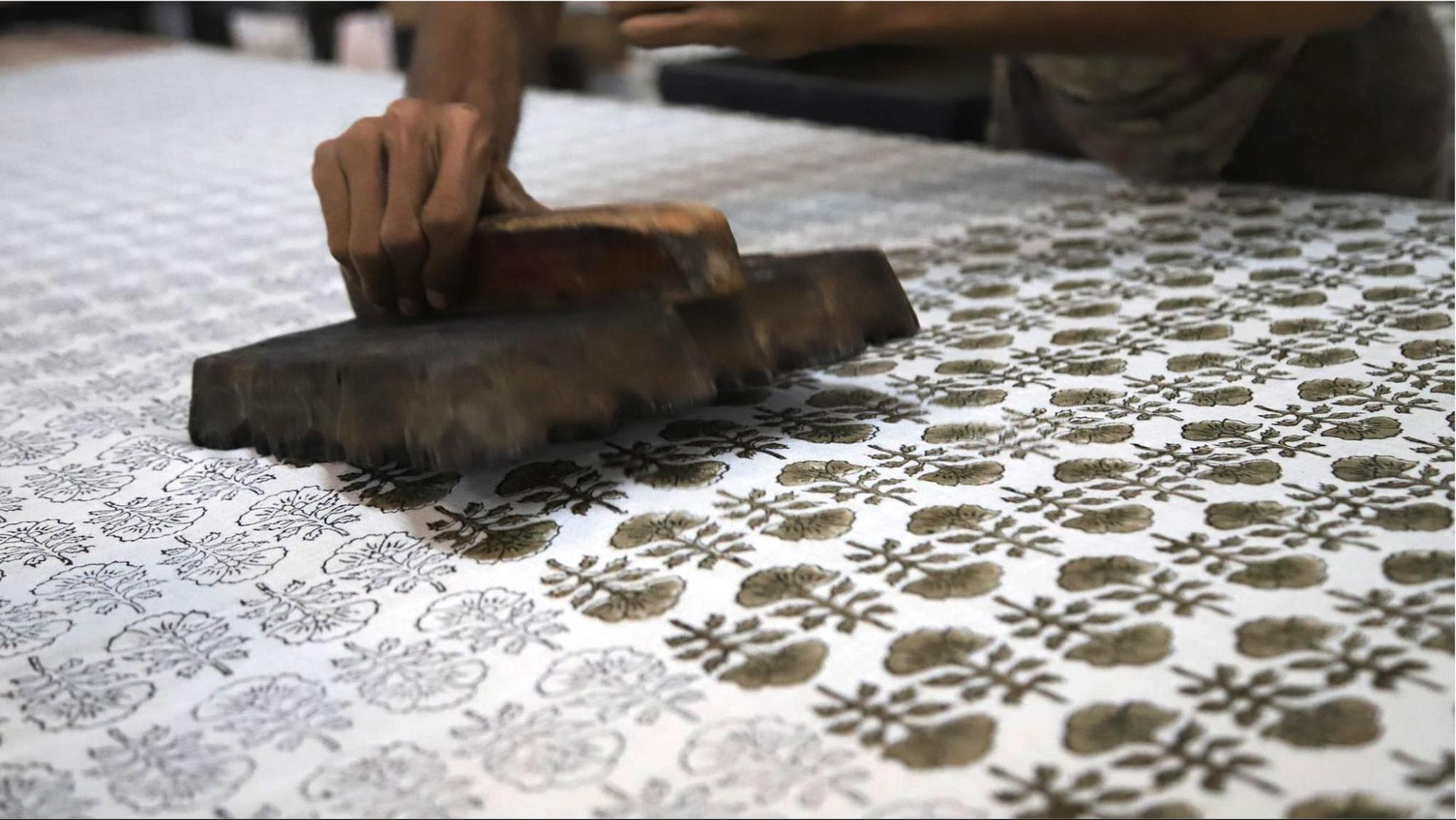 A skilled artisan block prints pattern on fabric. 