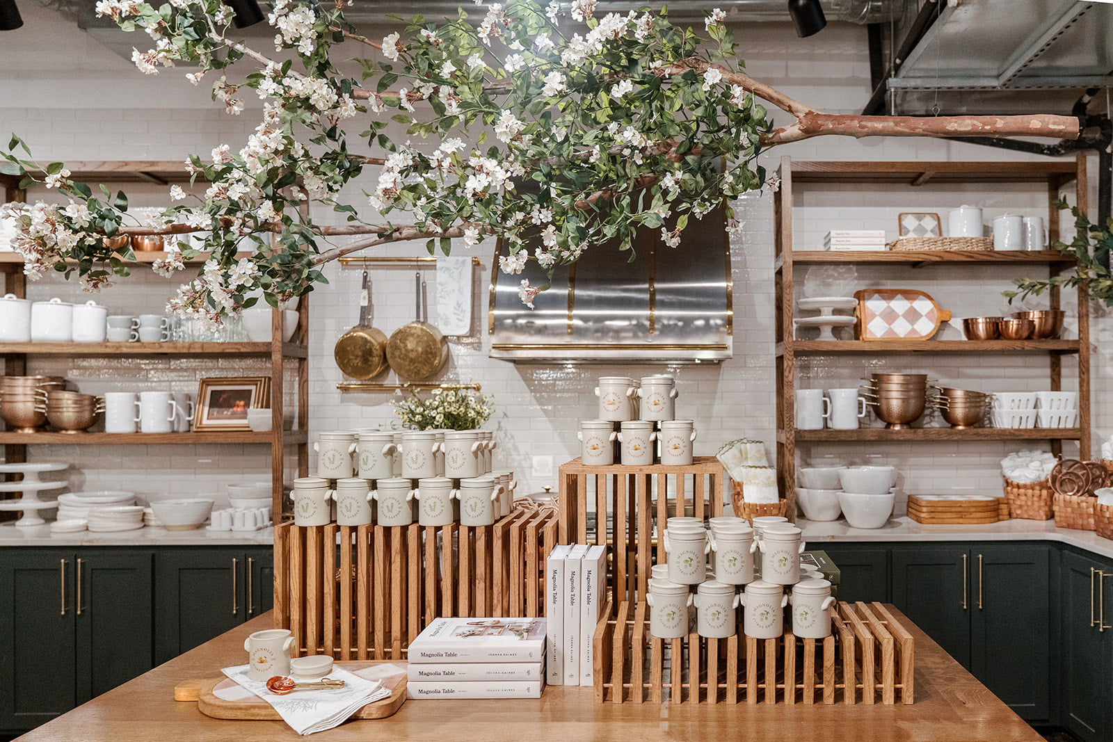 A foraged branch hangs above crates, candles, and cookbooks inside Magnolia Market.