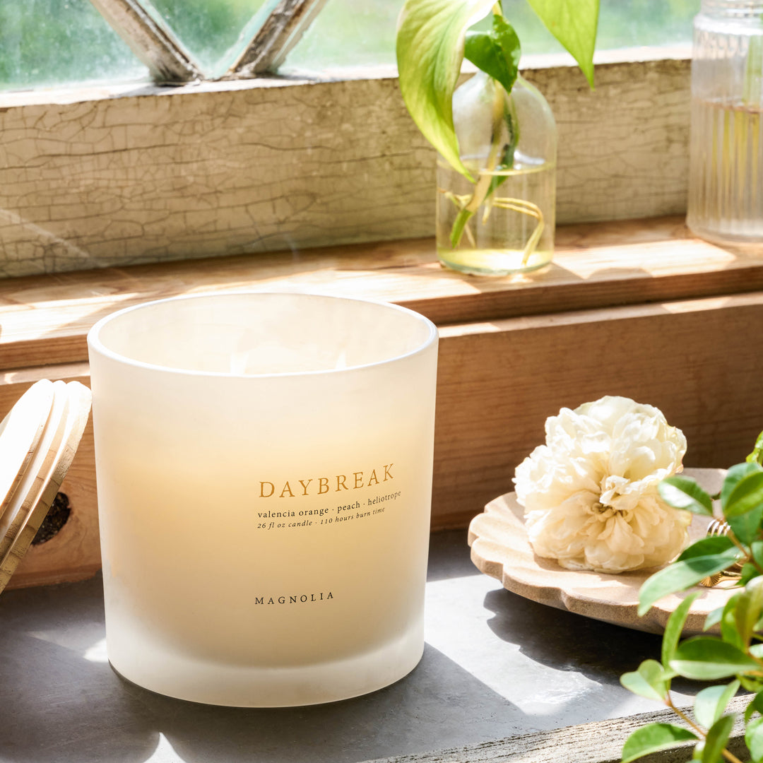 Magnolia's Daybreak Candle sits next to a tray with a flower.