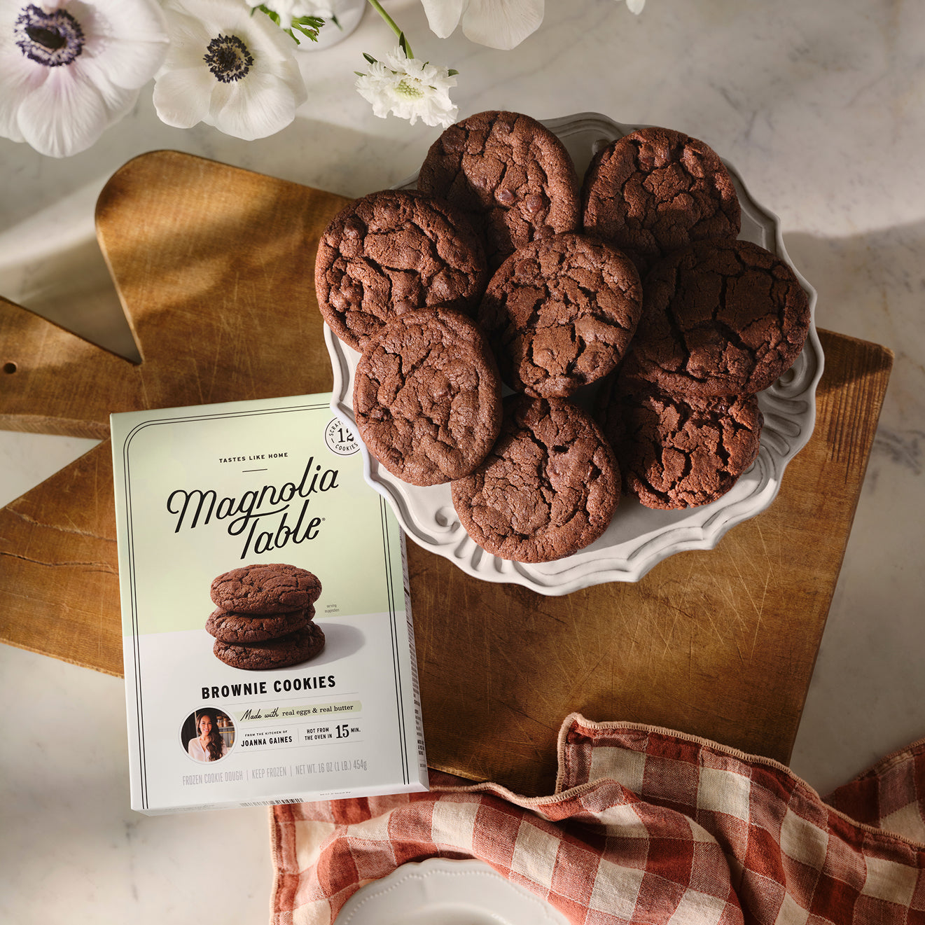 Plate of brownie cookies with Magnolia Table packaging on a wooden surface.