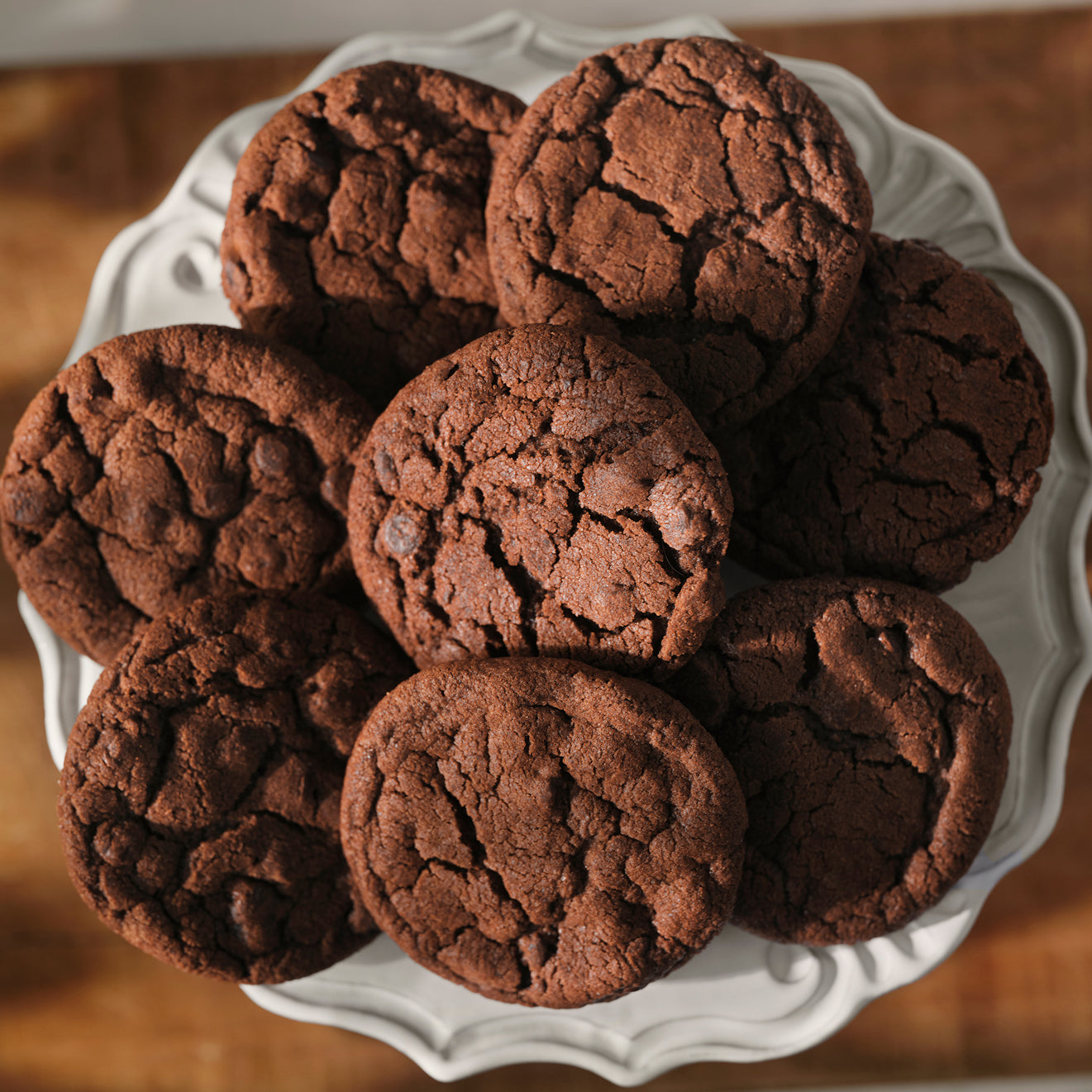 Chocolate cookies on a white plate with a wooden background