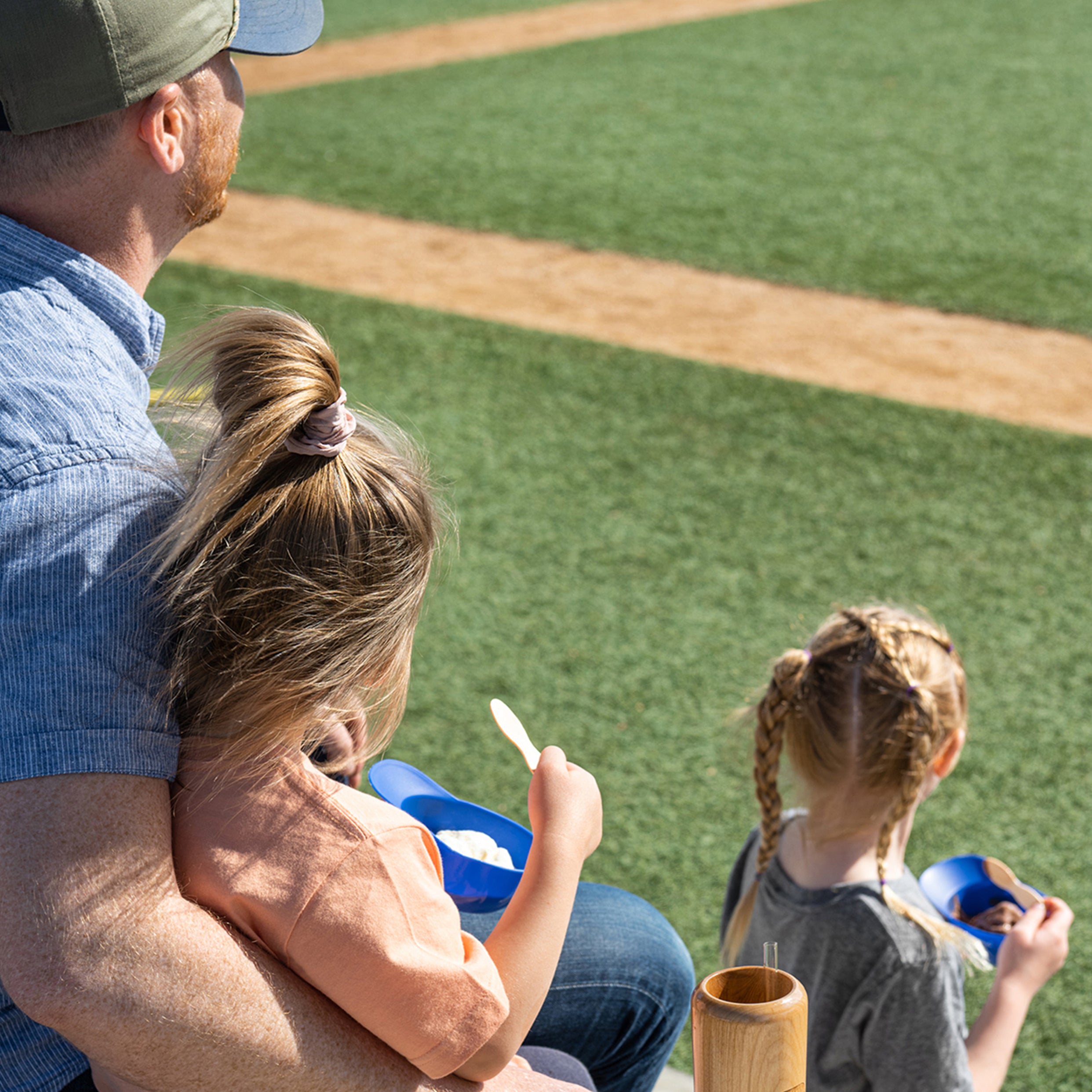 Man with two children sitting on a baseball field