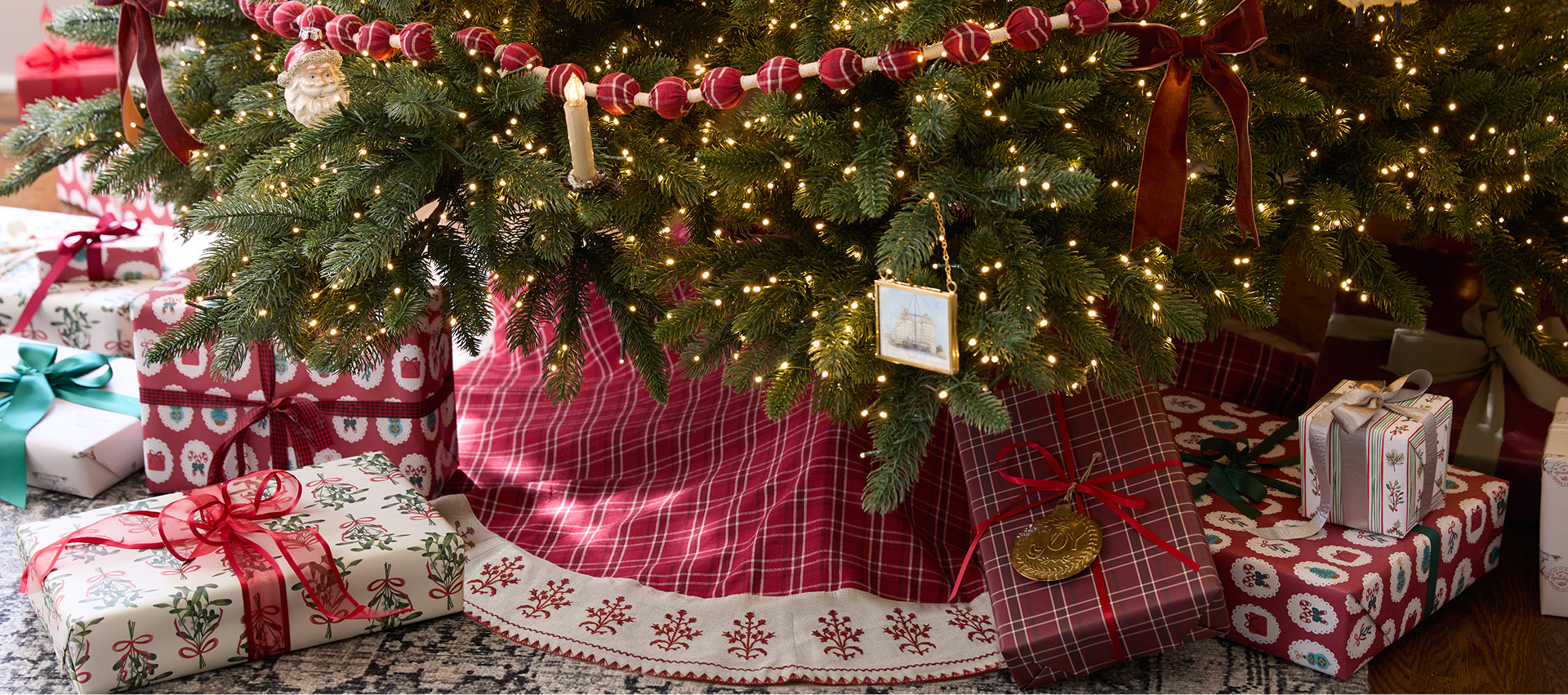 Decorated Christmas tree with presents underneath, surrounded by festive decorations.