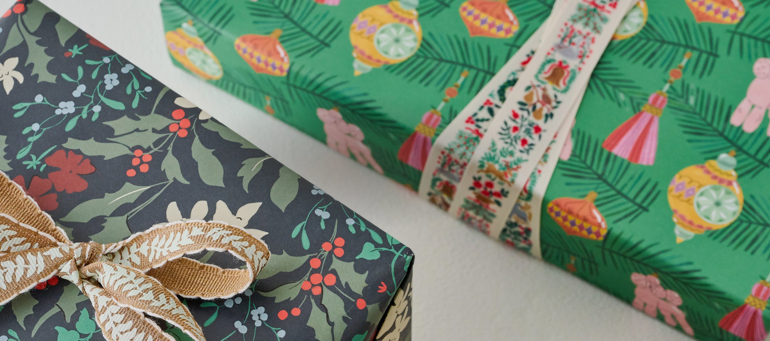Three gift boxes with floral and festive wrapping paper on a white surface.