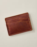 A brown leather cardholder wallet with visible stitching and card slots, photographed on a light neutral background.