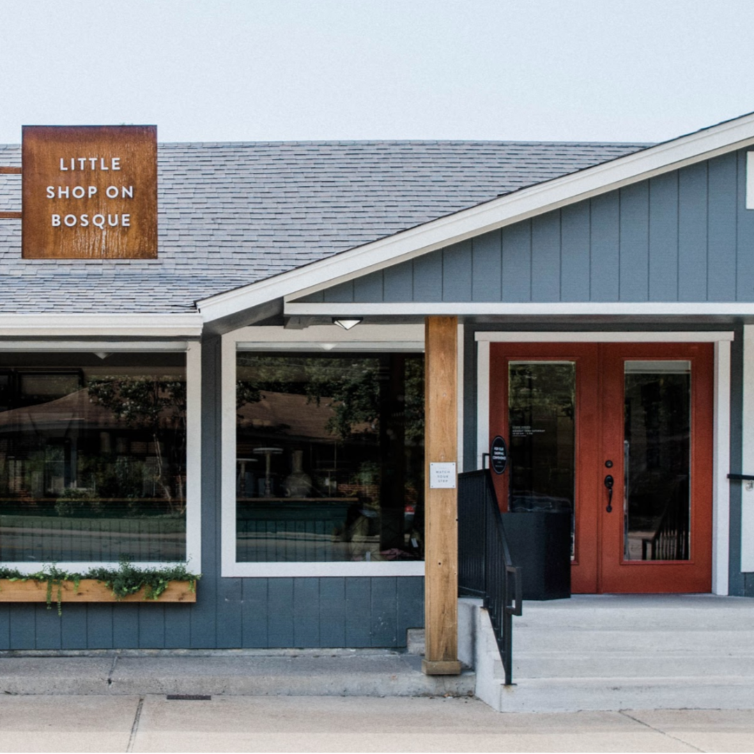 Storefront with 'Little Shop on Bosque' sign on a clear day