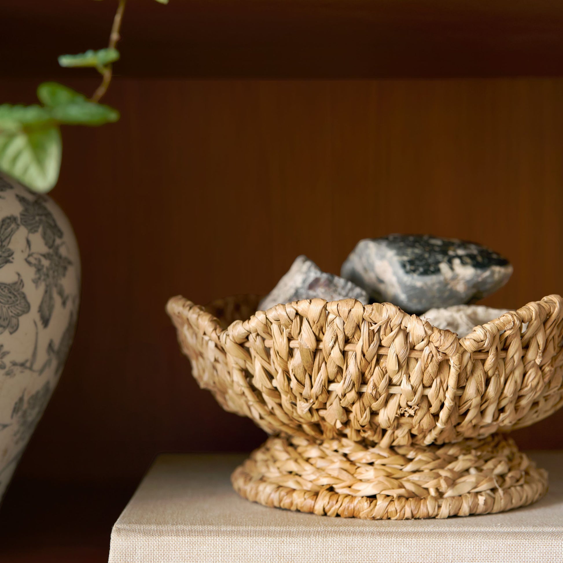 Solene Woven Scalloped Bowl filled with rocks on bookshelf