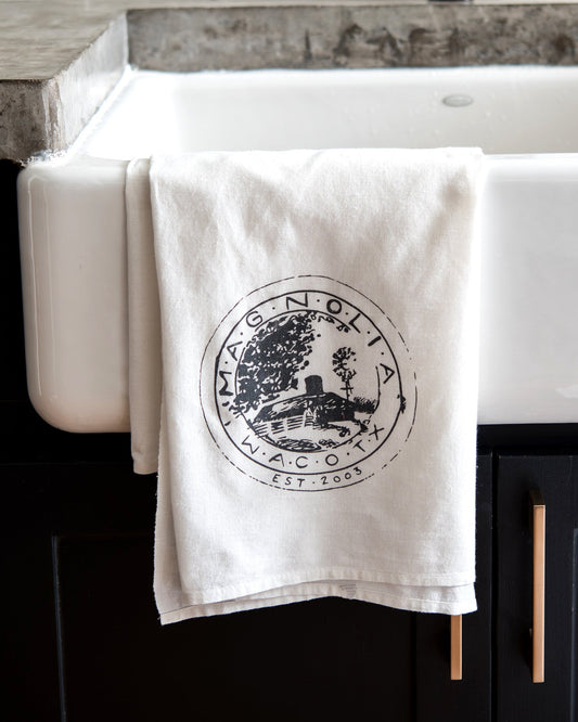 White towel with a black logo hanging on a wooden surface