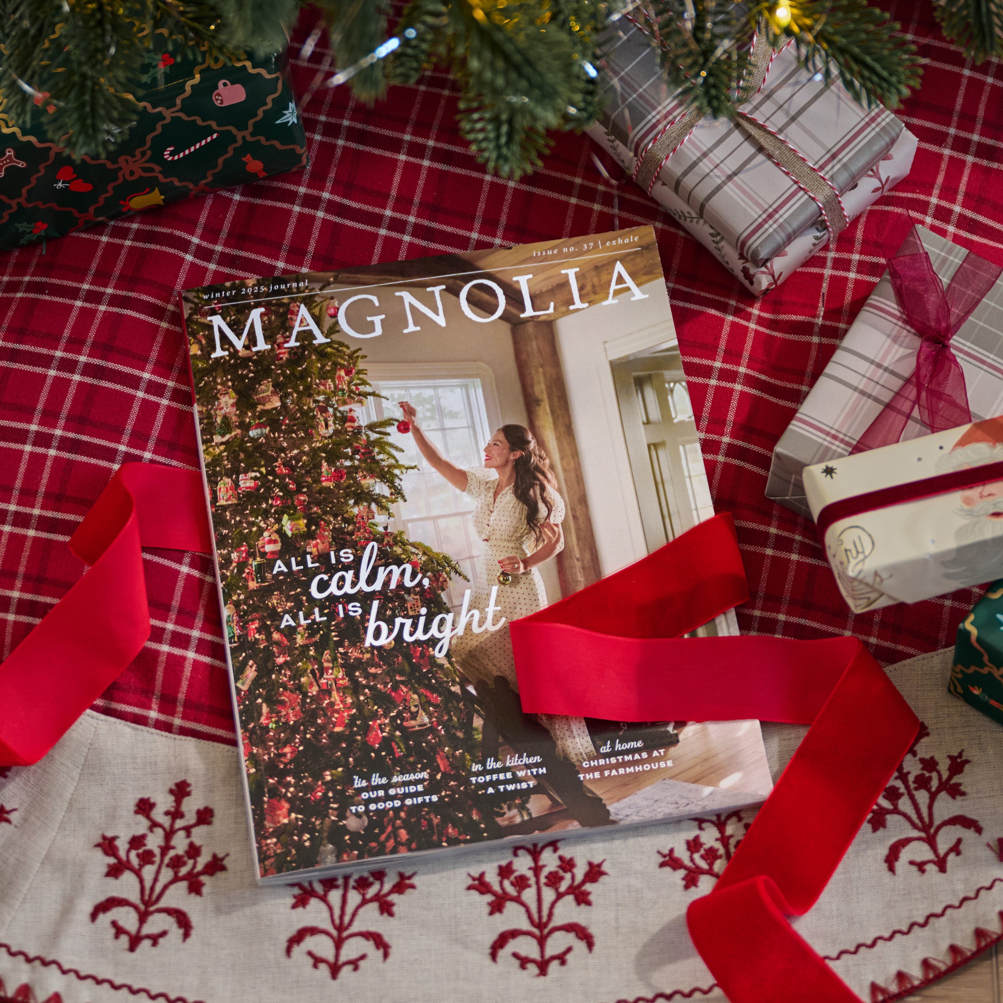 The Winter Magnolia Journal under a Christmas tree laying on a tree skirt with red ribbon.