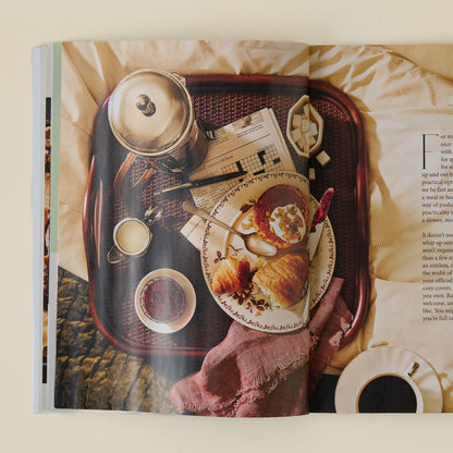 Magnolia Winter 2025 Journal picture captured of early morning breakfast of crossaint, grapefruit with coffee kettle and crossword puzzle.