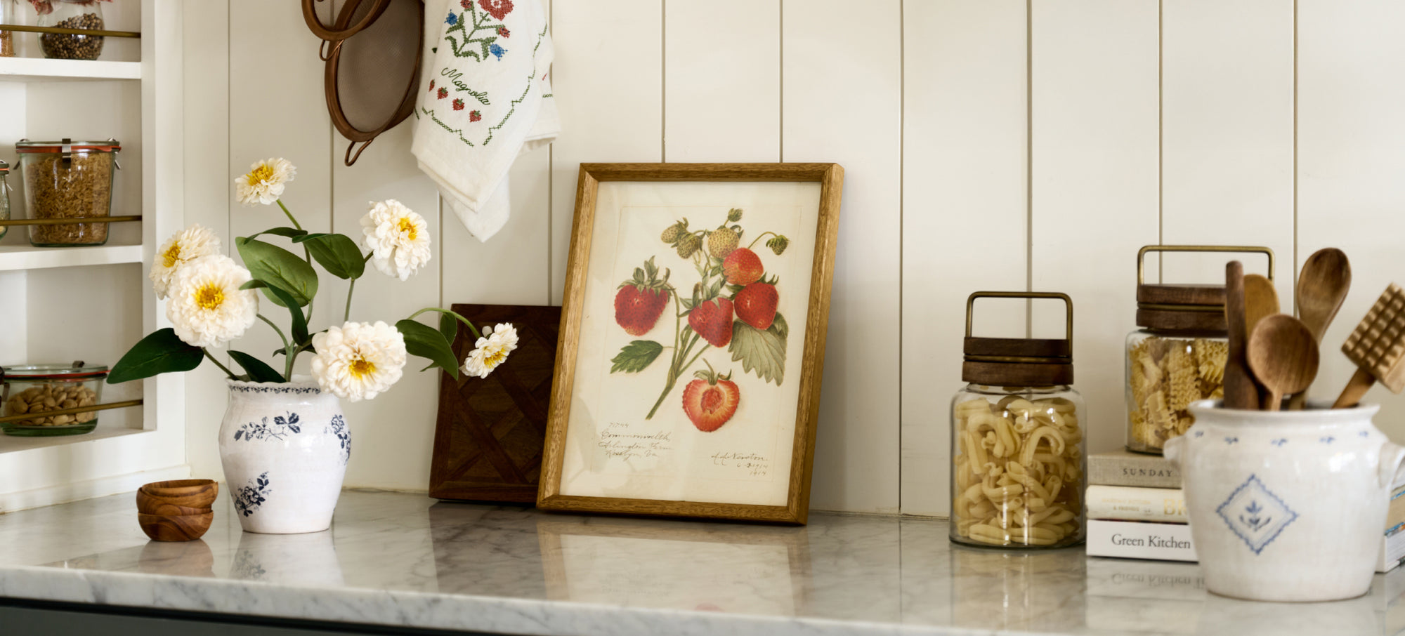 Kitchen counter with decorative items including a vase of flowers, framed print, and jars.