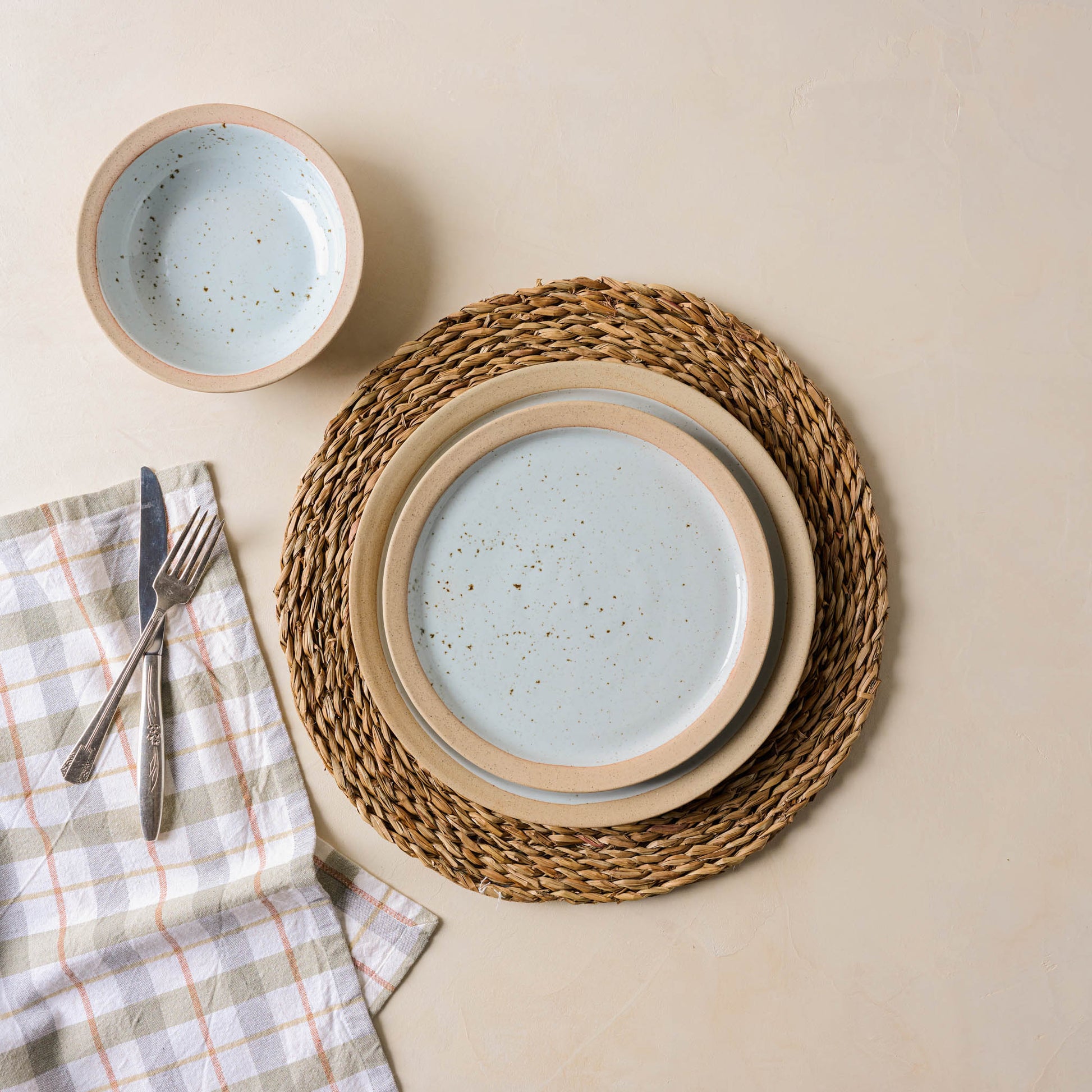 lucian round placemat underneath lillia plates and next to plaid napkin