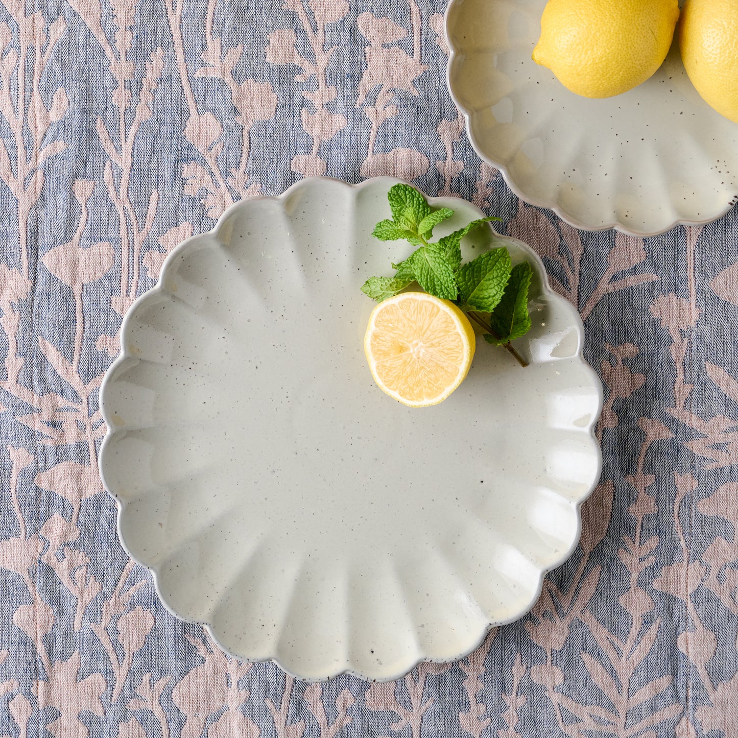 large grey scalloped plate with lemon on it next to small grey scalloped plate with lemons on it
