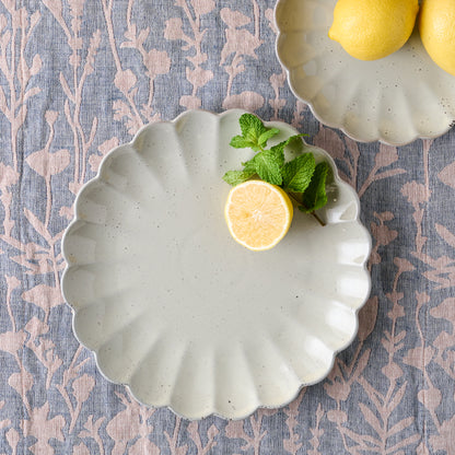 large grey scalloped plate with lemon on it next to small grey scalloped plate with lemons on it