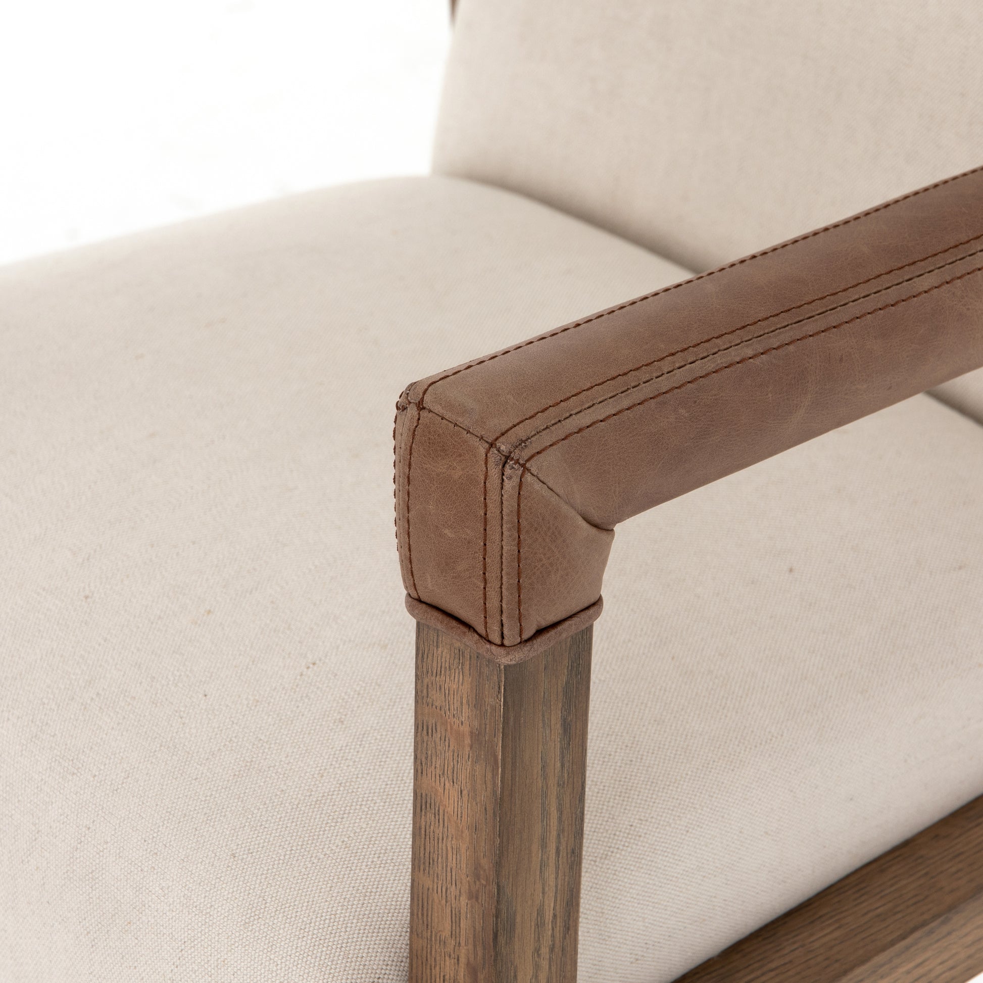 cream linen desk chair with leather-wrapped wooden arms and chrome metal base with wheels