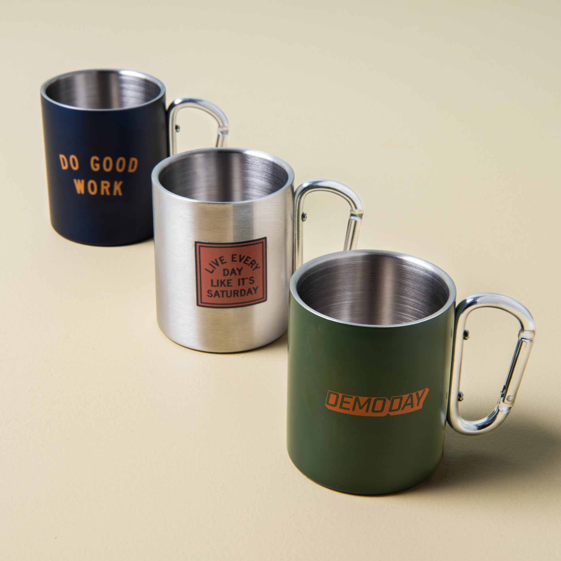 green stainless steel mug with "demoday" printed on the side with silver carabiner handle