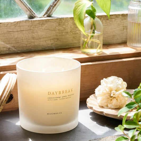 Magnolia Daybreak Candle next to flowers