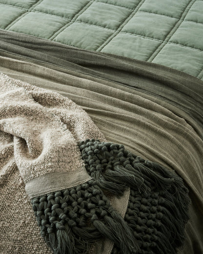 Dusty Green Tassel Throw at the foot of a made bed
