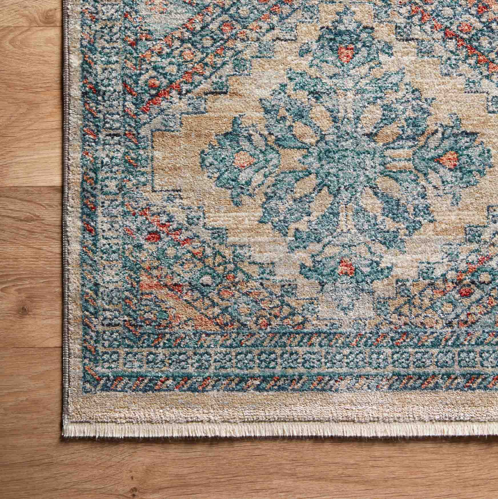 blue, orange, and tan diamond patterned rug with floral detail