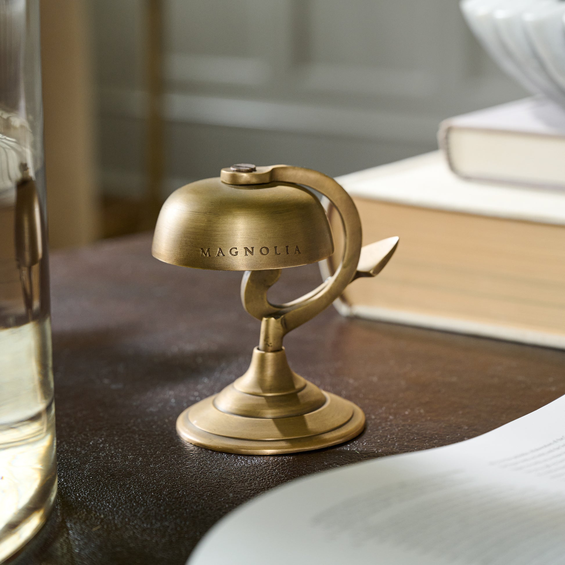 Antique Brass Bell engraved with Magnolia logo on a desk 