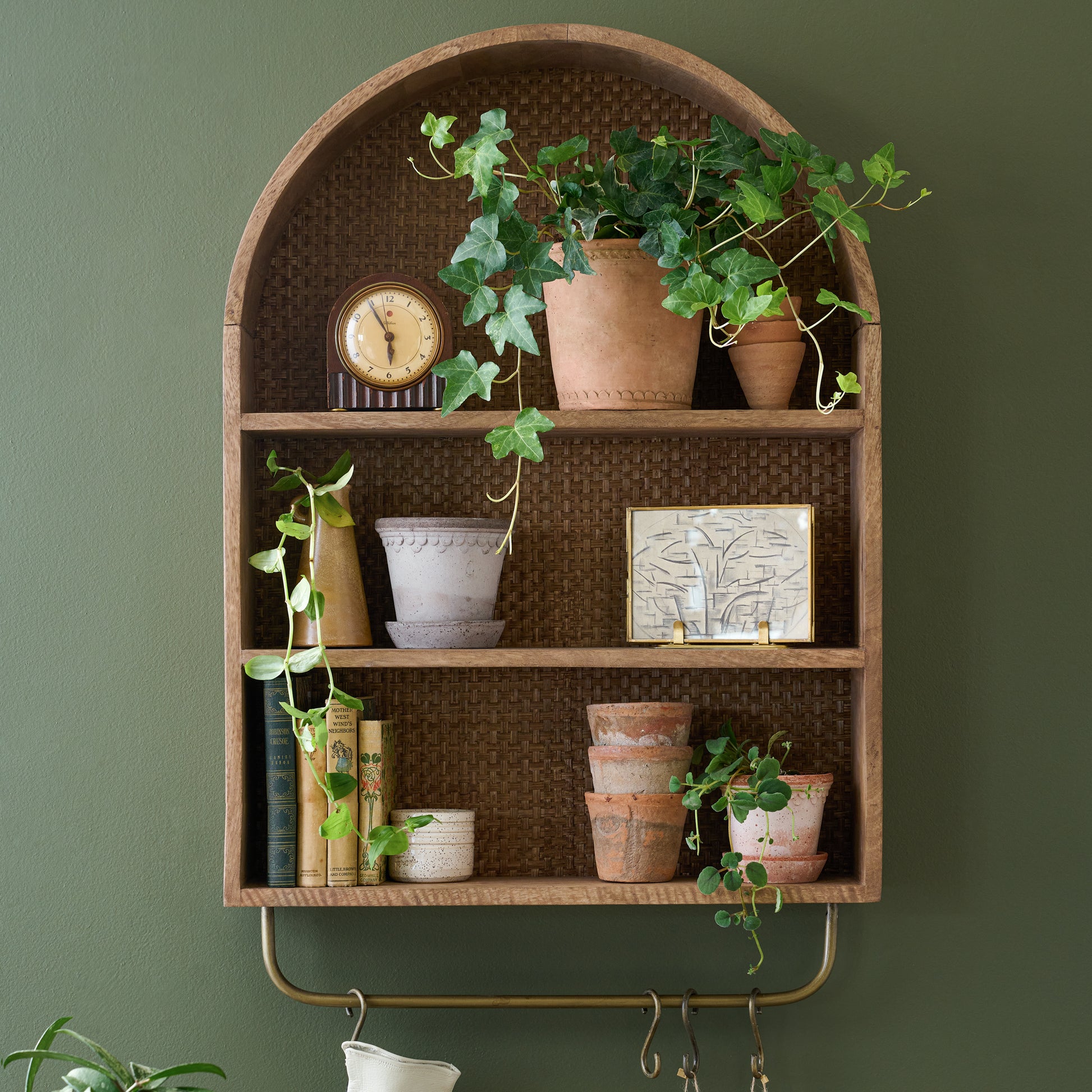 Belmar Arched Woven Wall Shelf with plants and pots and a clock on shelves