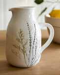 Pressed Floral Ceramic Pitcher on a table next to a glass of tea