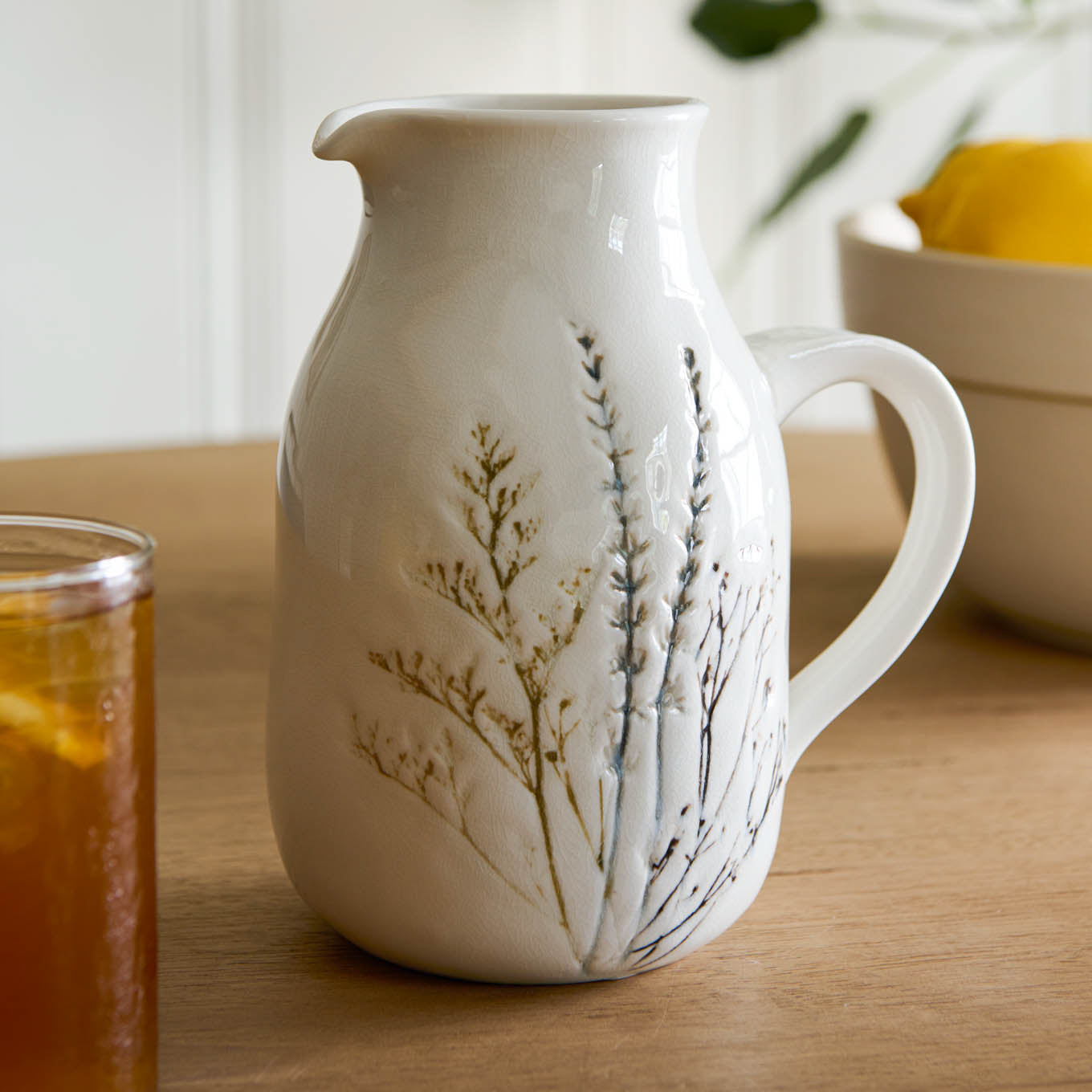 Pressed Floral Ceramic Pitcher on a table next to a glass of tea