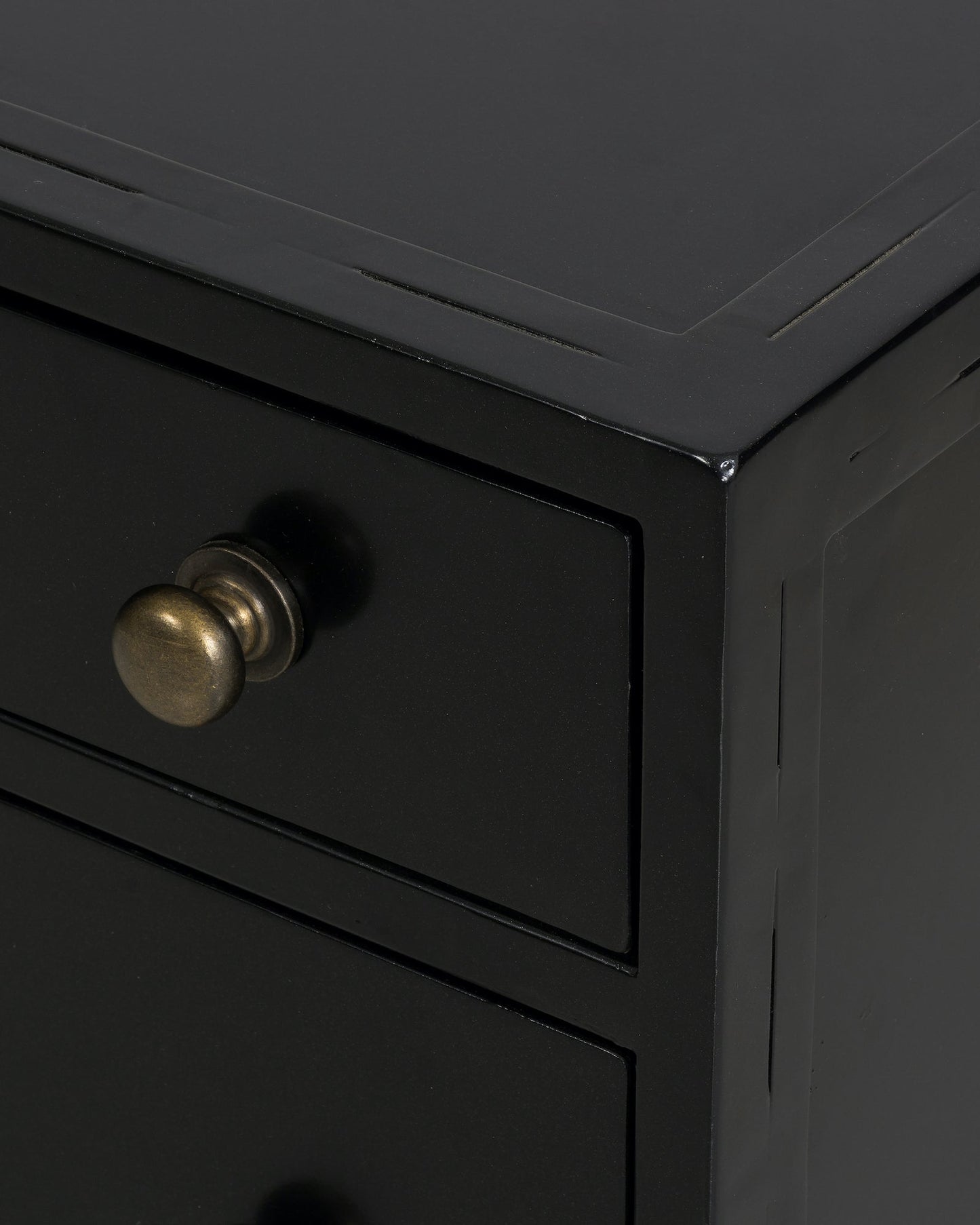 black metal nightstand with three drawers and brass knobs