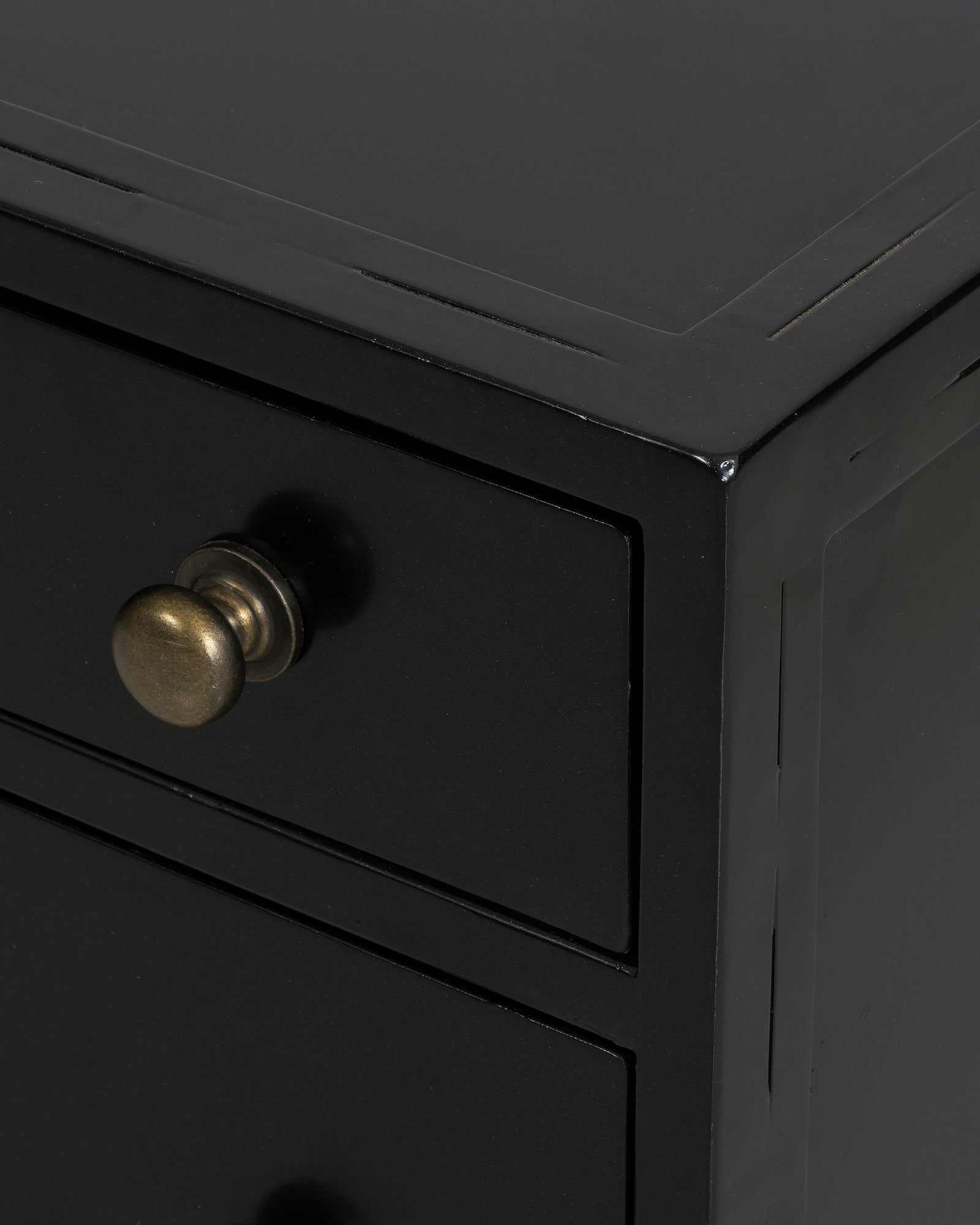 black metal nightstand with three drawers and brass knobs
