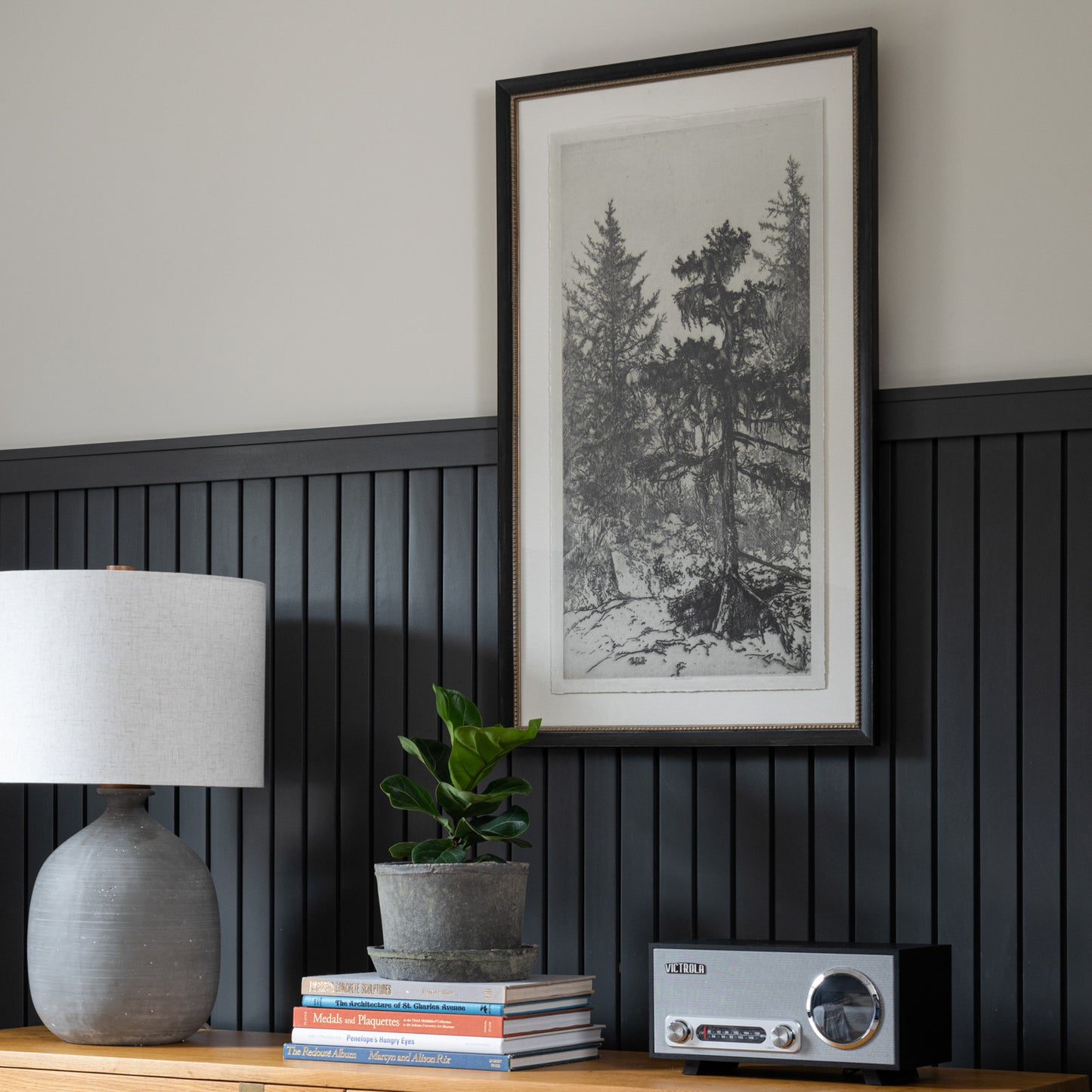 Framed wall art called Tall Trees II hanging on wall above wood dresser