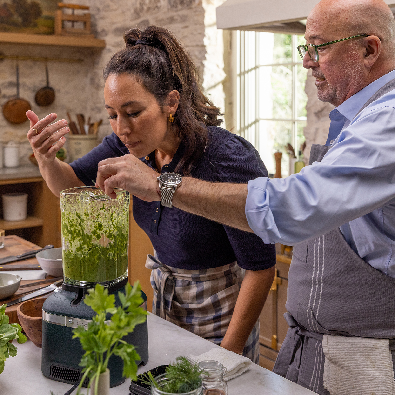 Joanna gaines smells a green mixture in a blender with a man in her gristmill kitchen