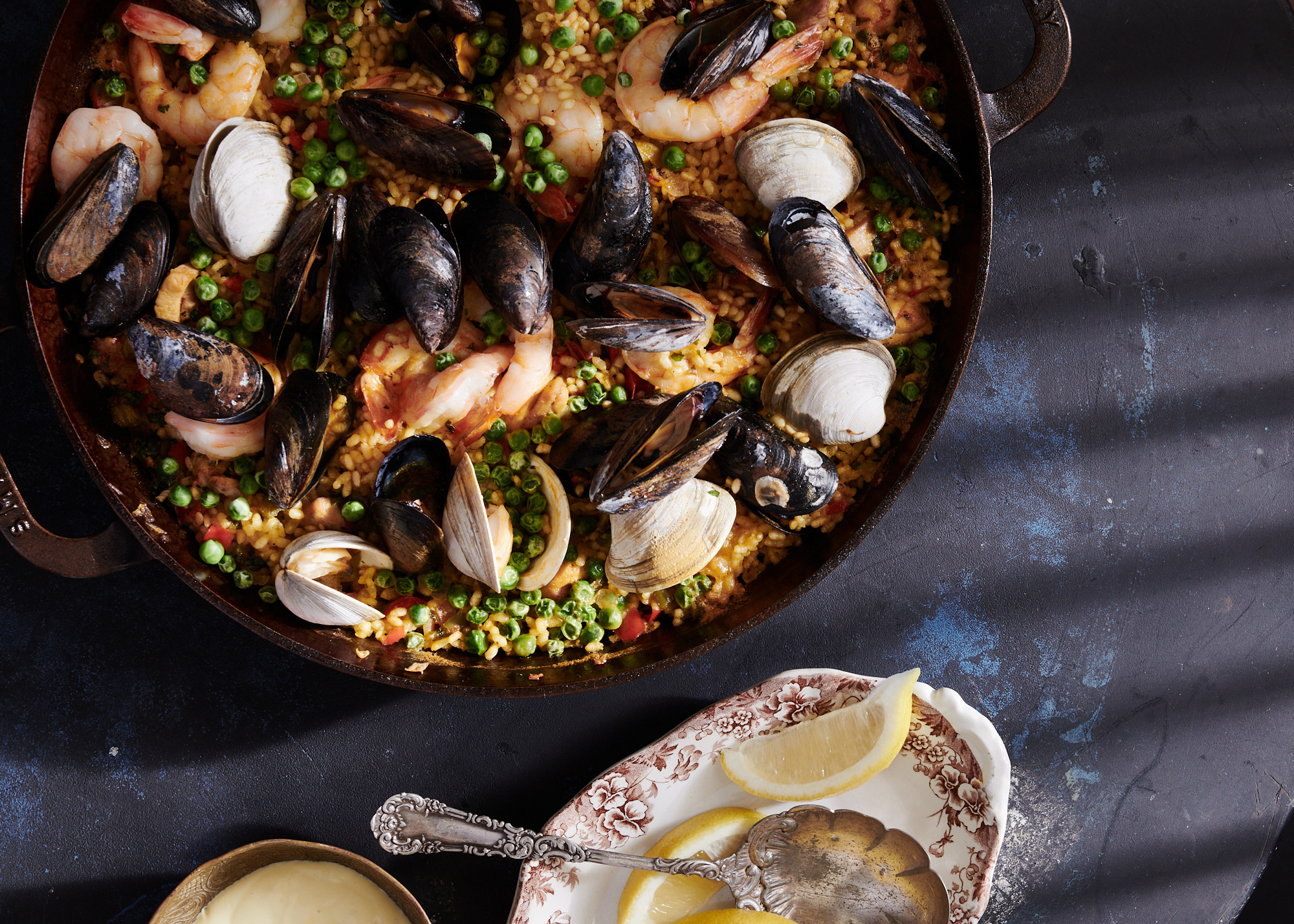 a bowl with mussels, peas and shrimp is pictured next to a bowl of lemons