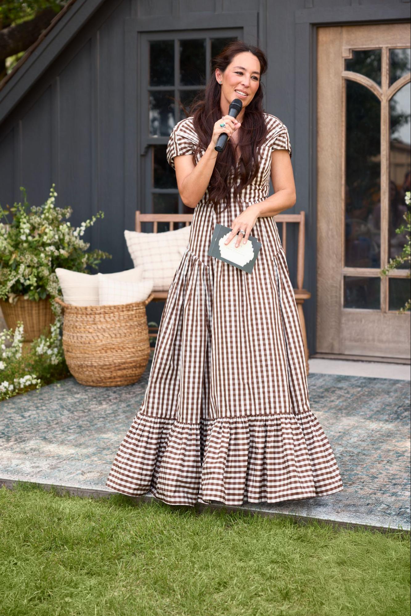 Joanna Gaines smiling and talking into a microphone on the Castle lawn in Waco, Texas.