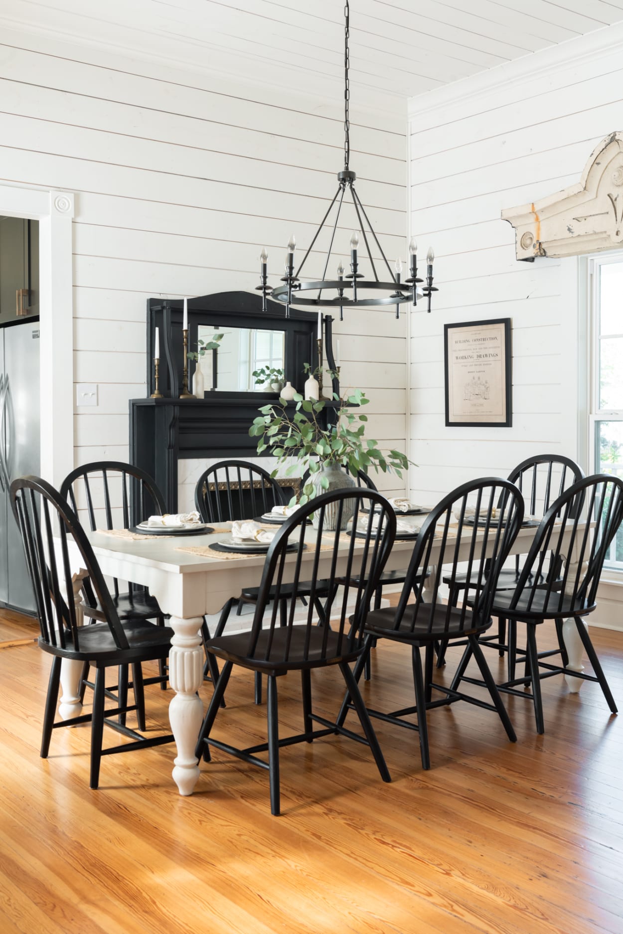 Farmhouse style dining room with shiplap walls, black painted fireplace and chairs, and white farm table - Magnolia House in McGregor, TX.