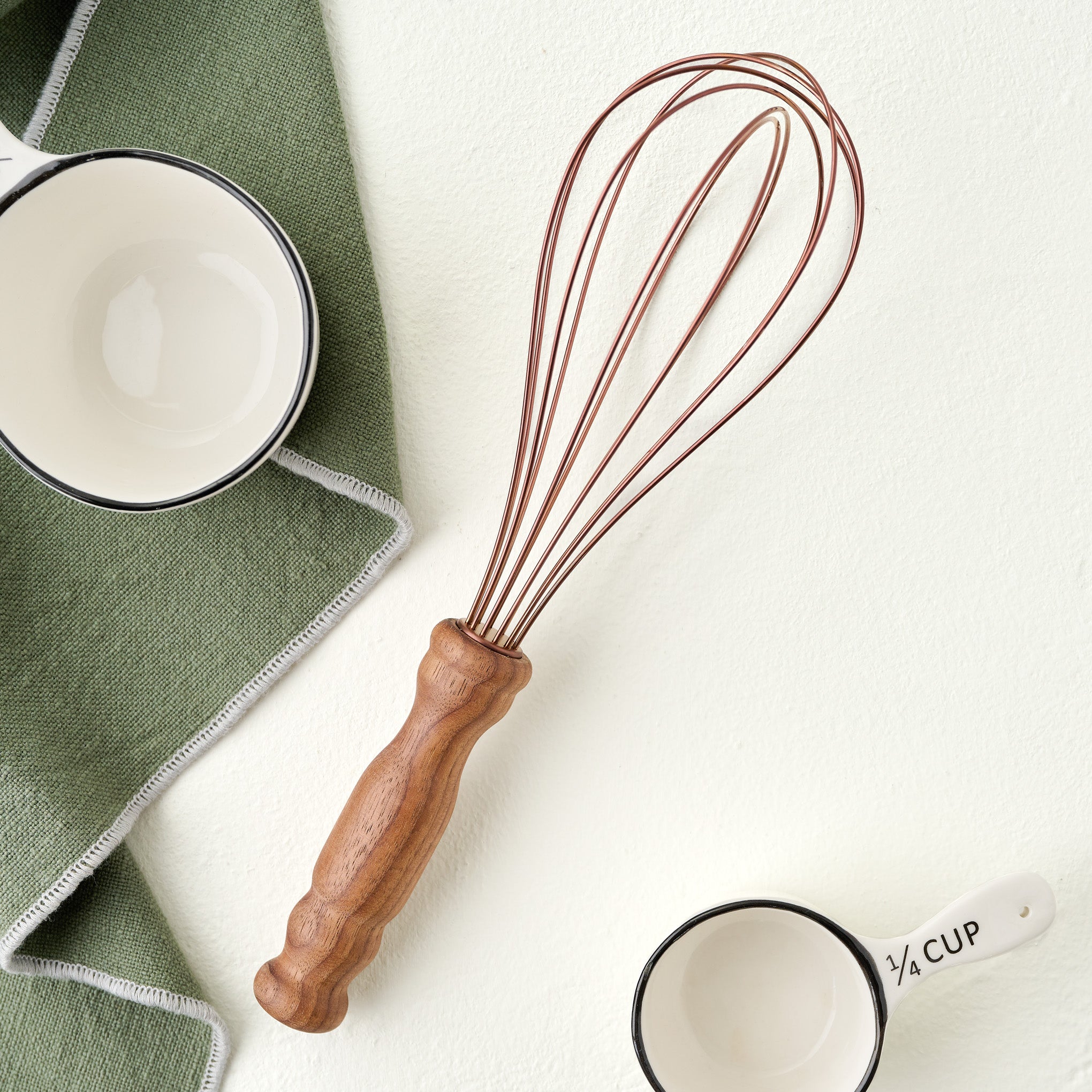 Copper and Walnut Whisk shown with measuring cups and kitchen towel $24.00