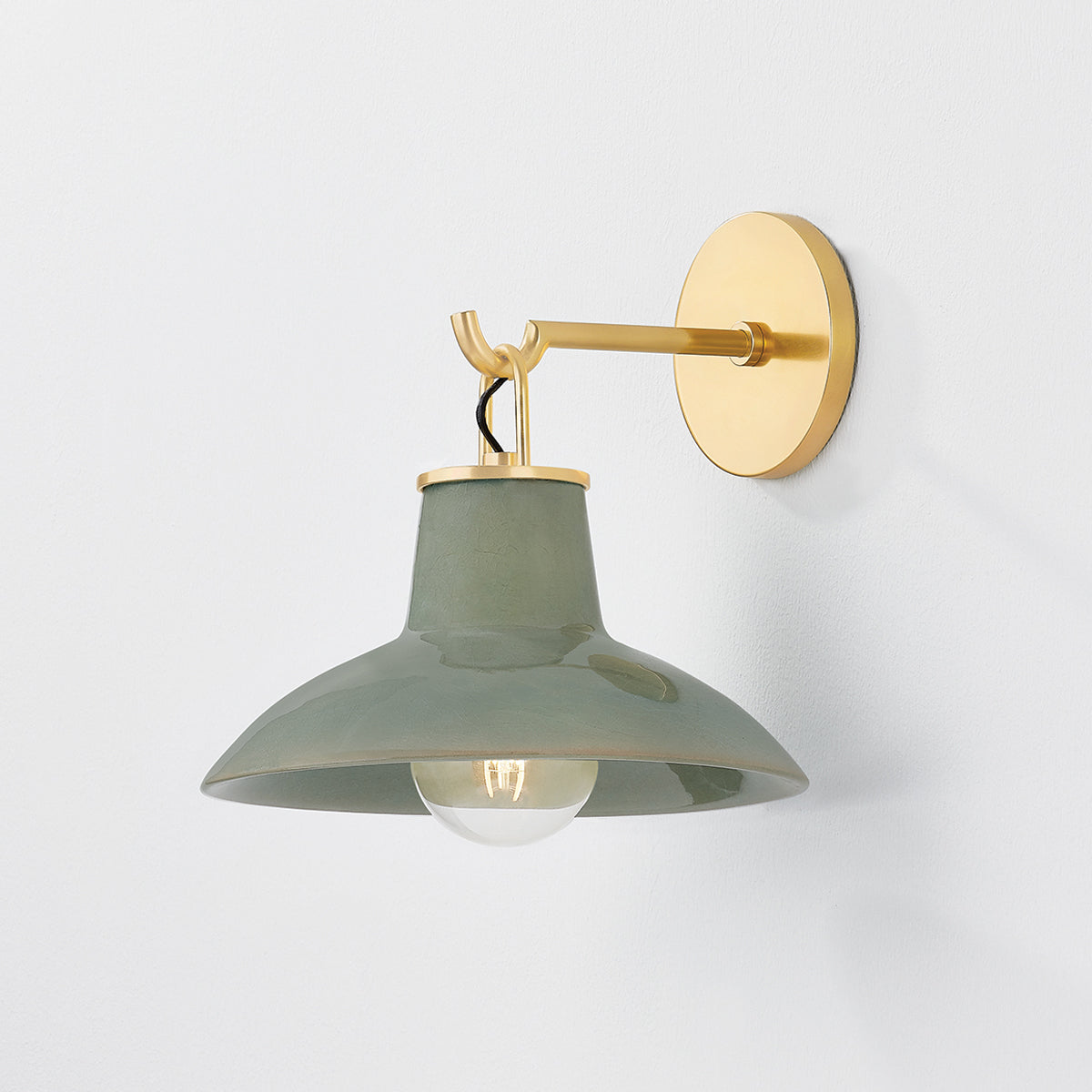 Justine Sconce in color Aged Brass with Ceramic Moss Crackle shown with light on