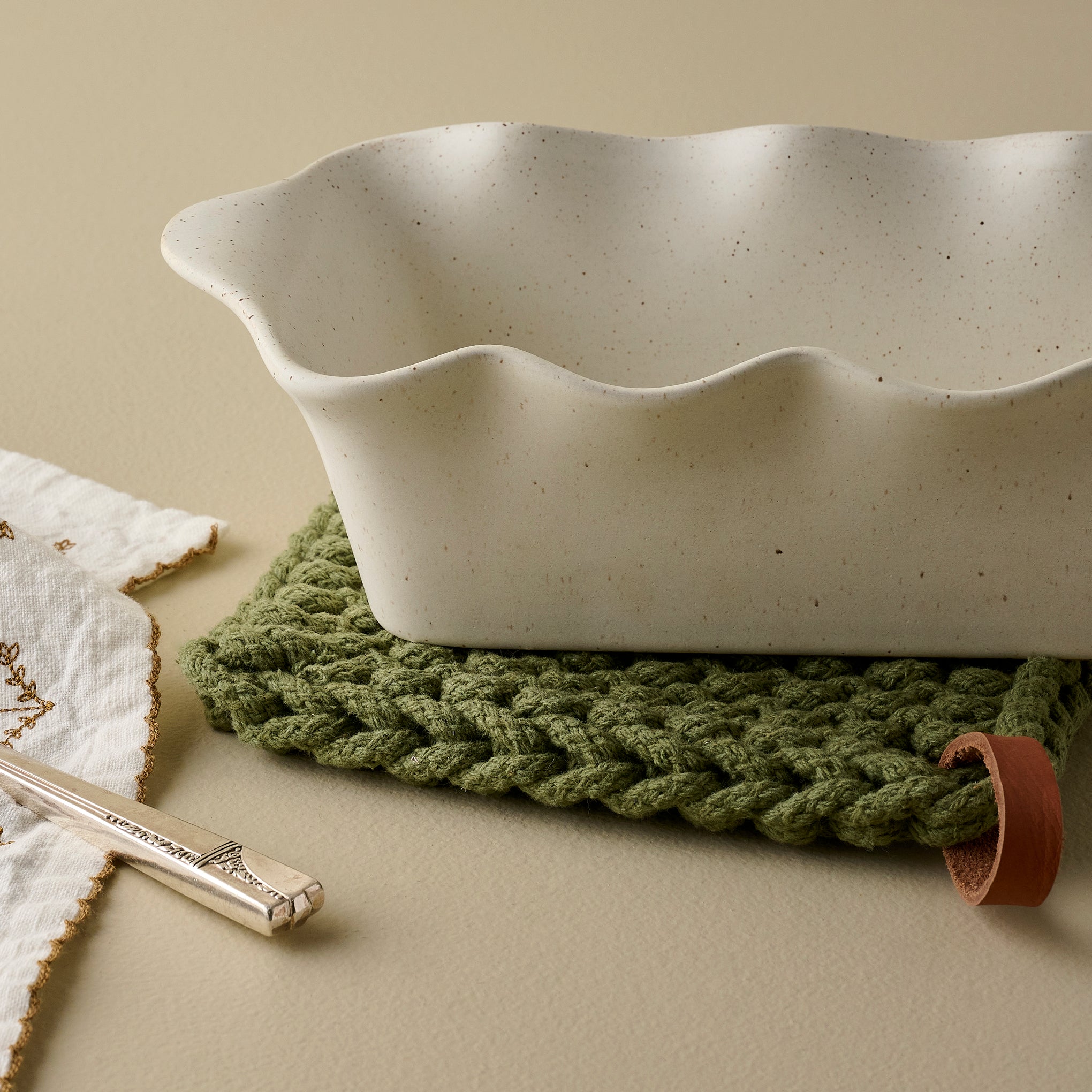 French White Scalloped Loaf Pan shown up close on pot holder $40.00