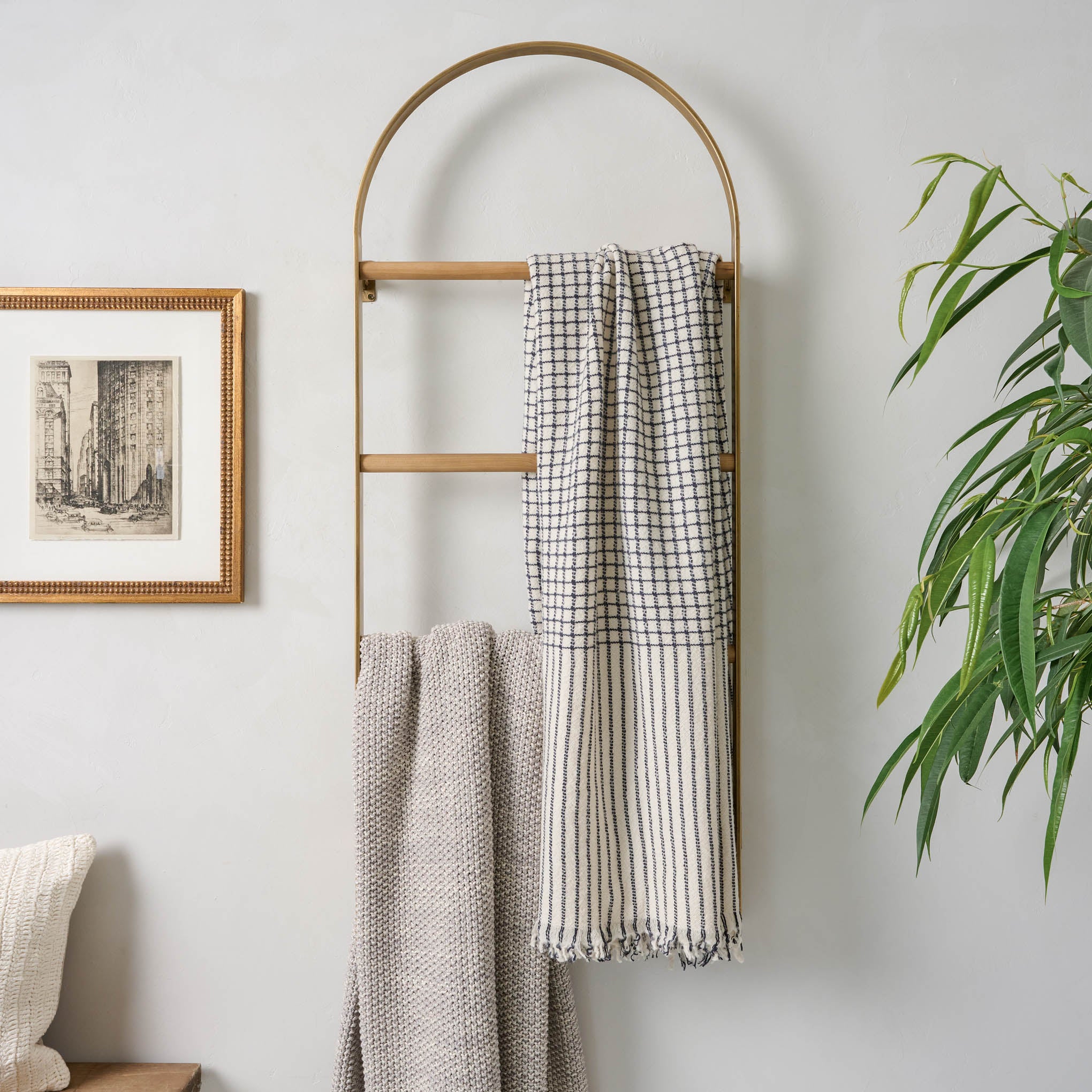 Antique Brass Carmen Wall Ladder against a wall with throw blankets hanging on it