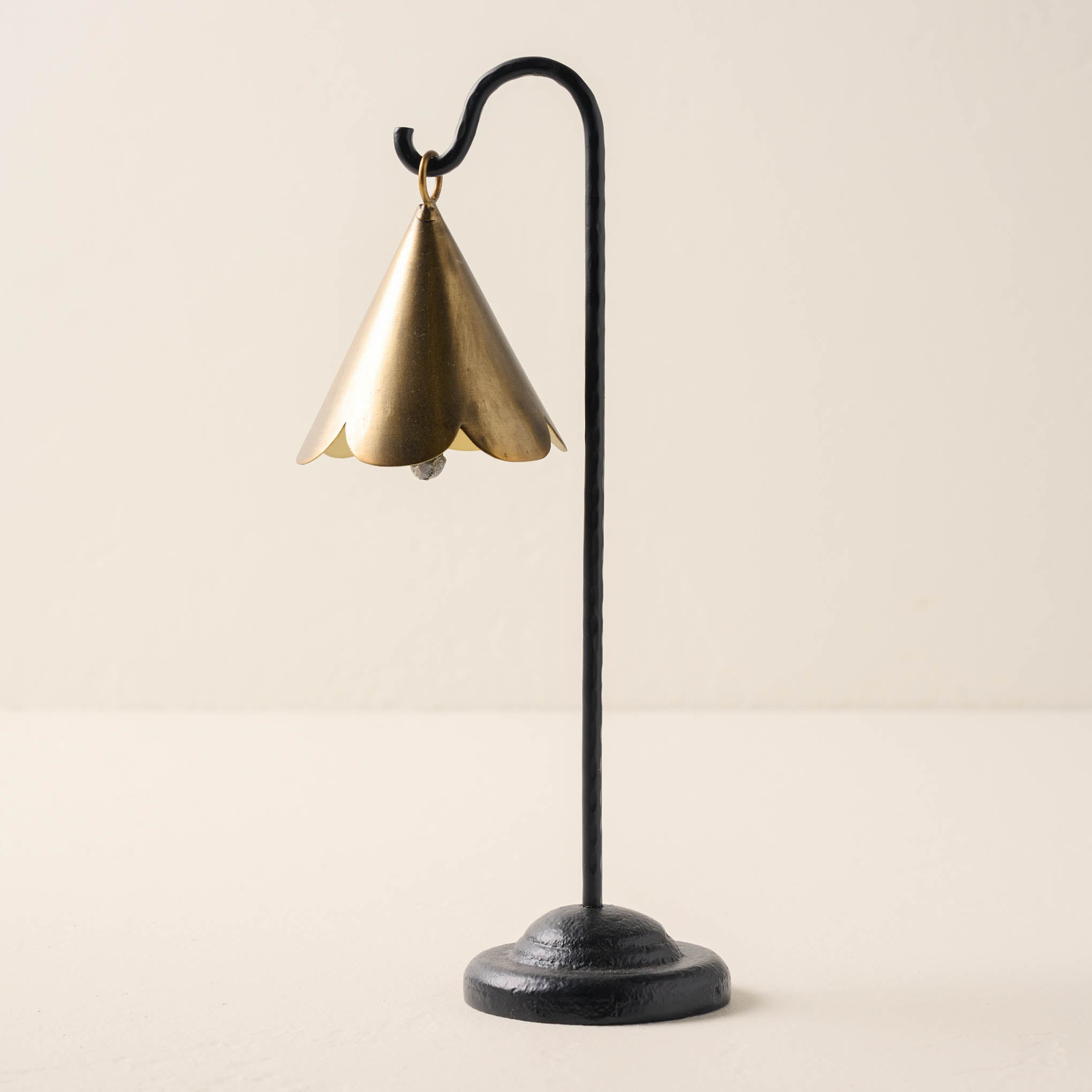 large sized brass scallop bell hanging from black metal stand